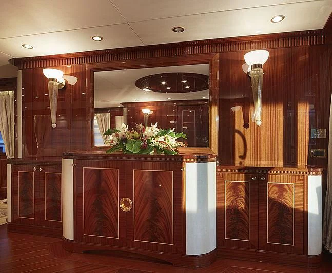 a room with a wood cabinet and a mirror with a vase of flowers on it aboard FORWIN Yacht for Sale