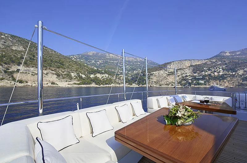 a table on a deck overlooking a city and mountains aboard FORWIN Yacht for Sale