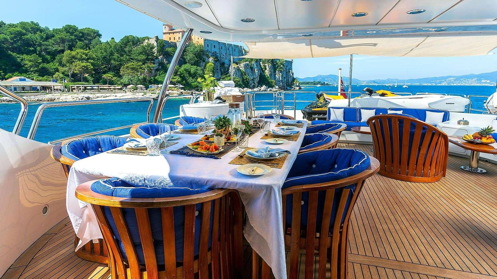 a table set for a meal on a deck overlooking a beach aboard NEW STAR Yacht for Charter