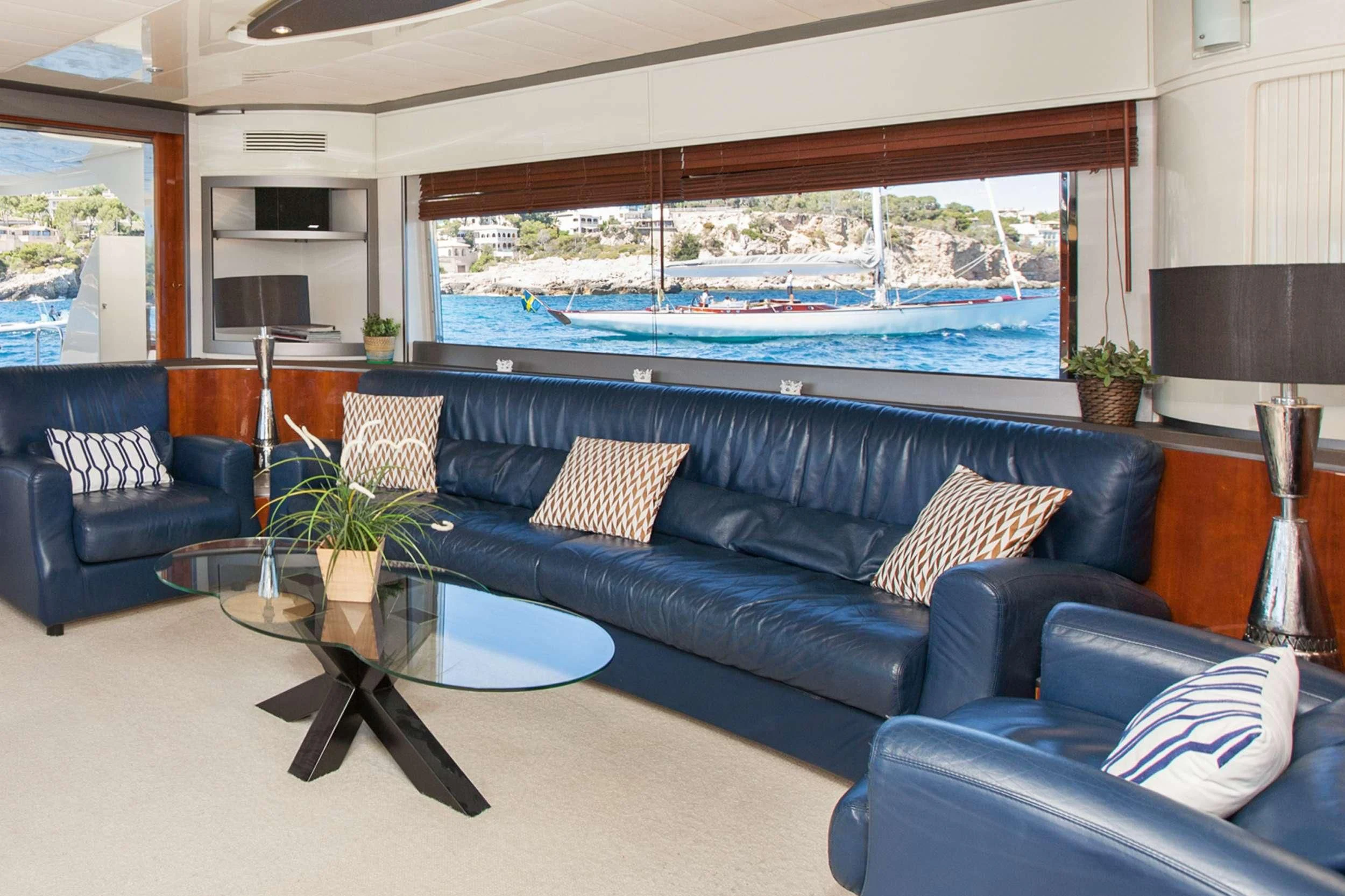 a living room with a large blue couch and a large window aboard WHITE FANG Yacht for Sale