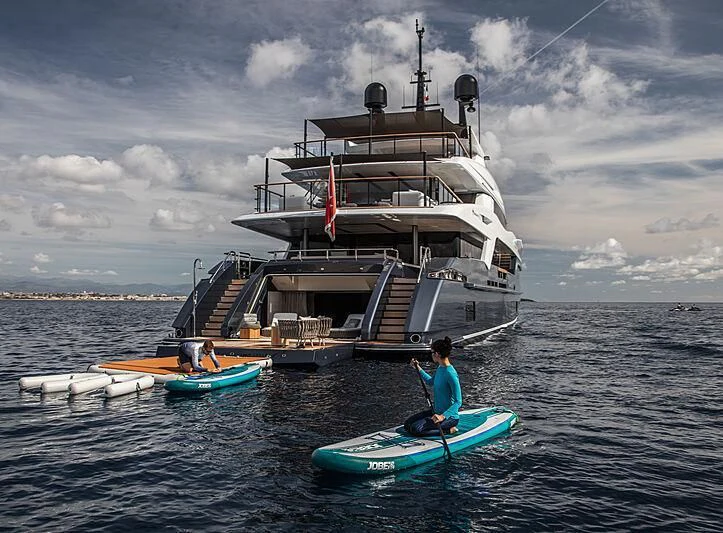 a person on a surfboard next to a boat in the water aboard SEVERIN°S Yacht for Charter