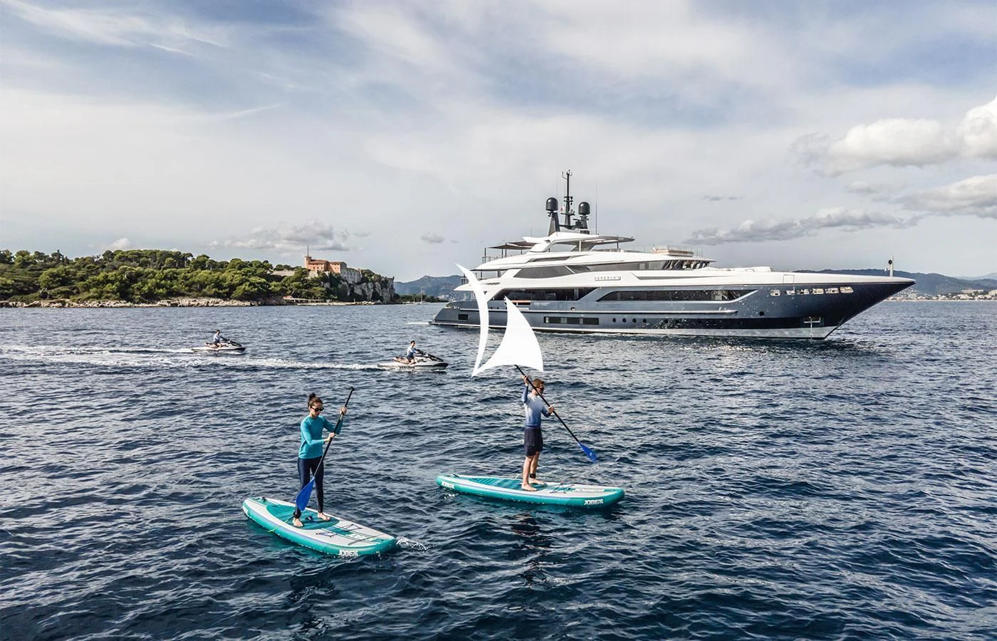 a couple of people on surfboards in the water with a boat in the background aboard SEVERIN°S Yacht for Charter