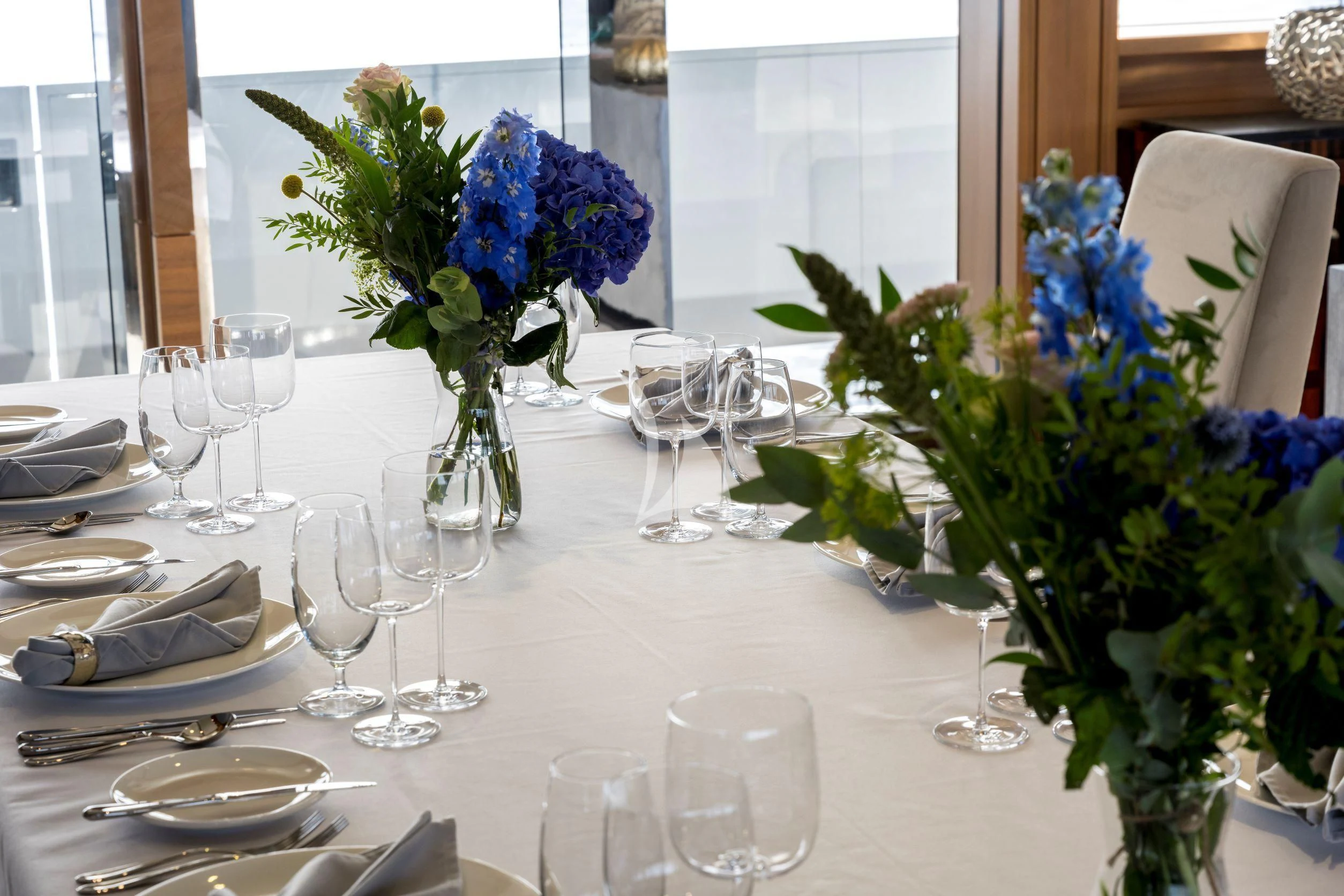 a table with wine glasses and flowers aboard NAVIS ONE Yacht for Charter