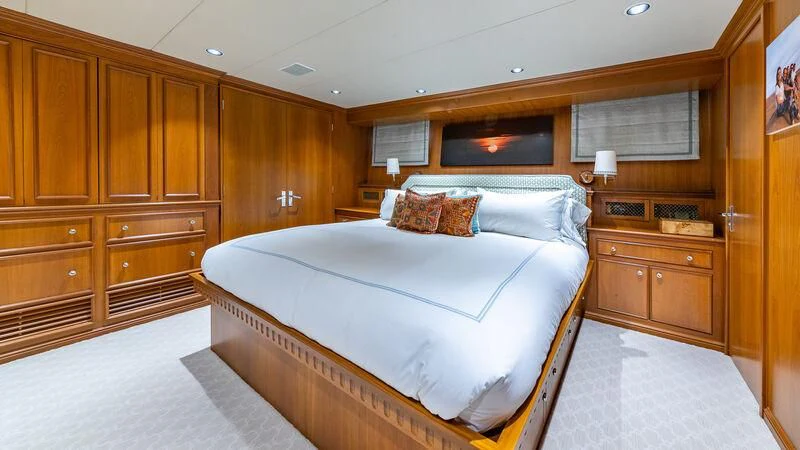 a bedroom with a bed and a wood cabinet aboard SEAQUEL Yacht for Sale