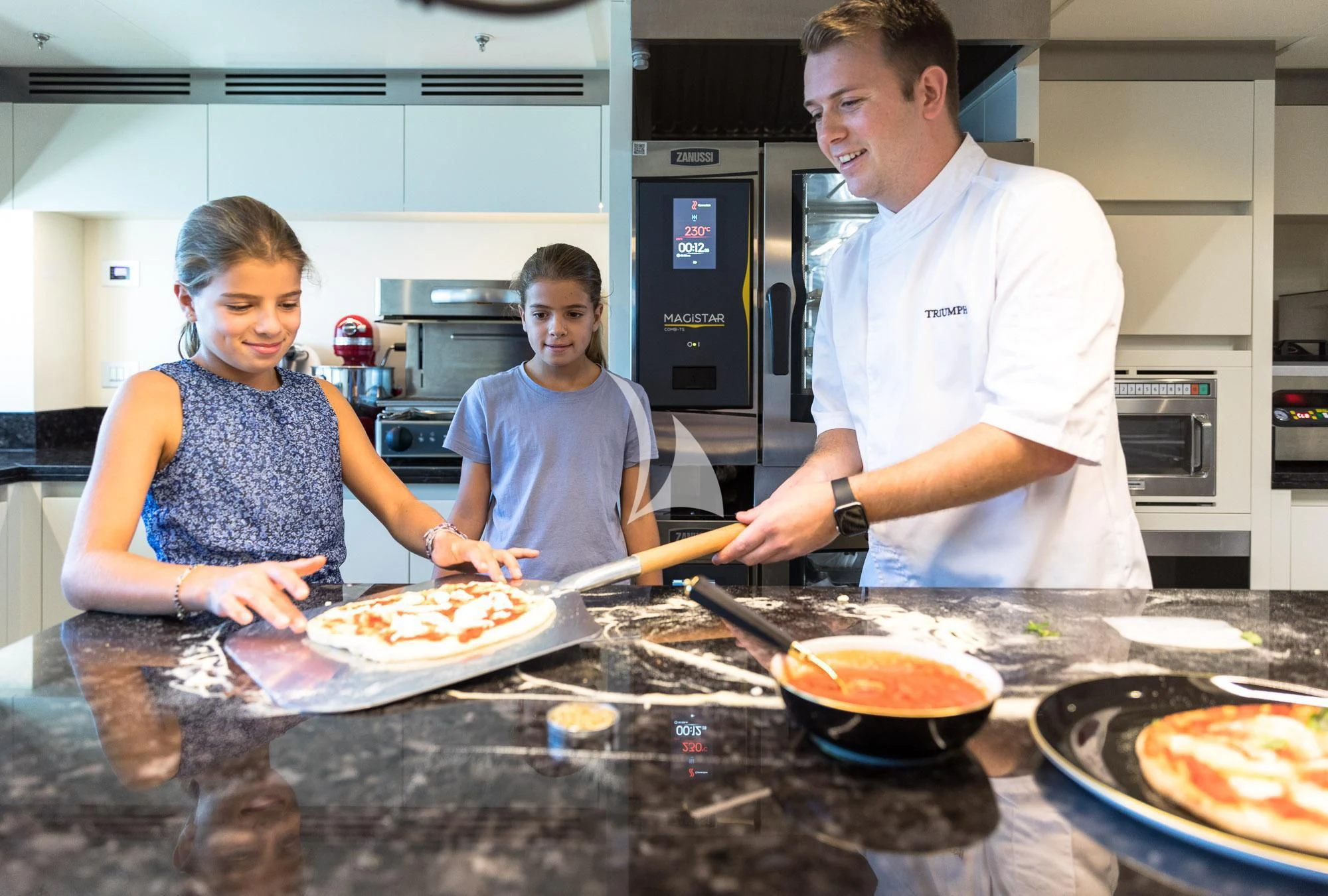 a man and woman cooking pizza aboard TRIUMPH Yacht for Sale