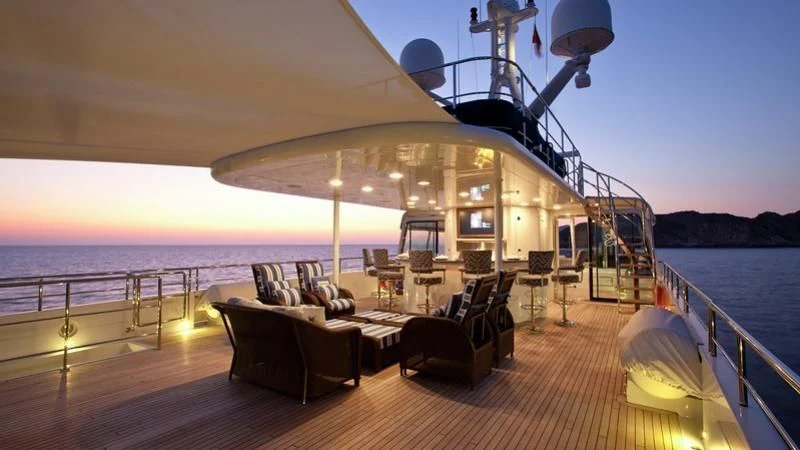 a deck with a large boat on it and a couch and chairs on it aboard EMELINA Yacht for Sale