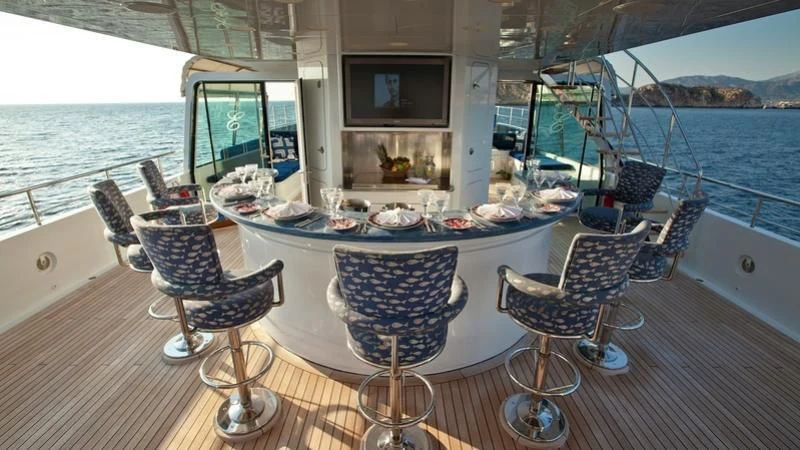 a table with chairs and a television on it aboard EMELINA Yacht for Sale