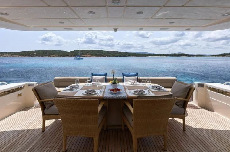 a table set for a meal on a deck overlooking a body of water aboard PORTHOS SANS ABRI Yacht for Sale