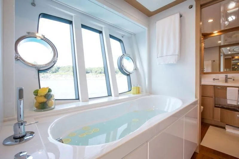 a bathroom with a tub sink and a window aboard PORTHOS SANS ABRI Yacht for Sale