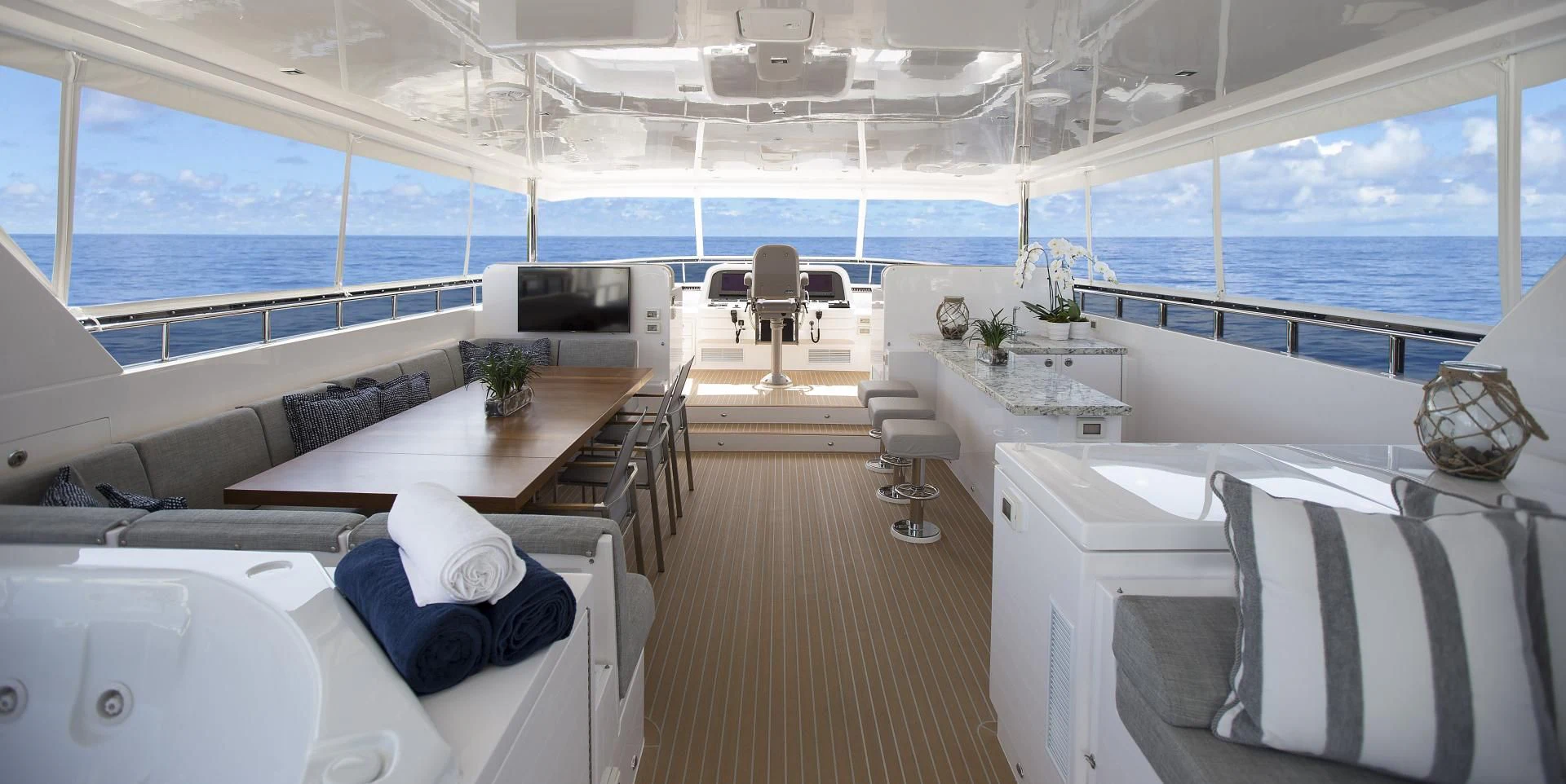 a room with a large window and a table with chairs and a television aboard SEASEID Yacht for Sale