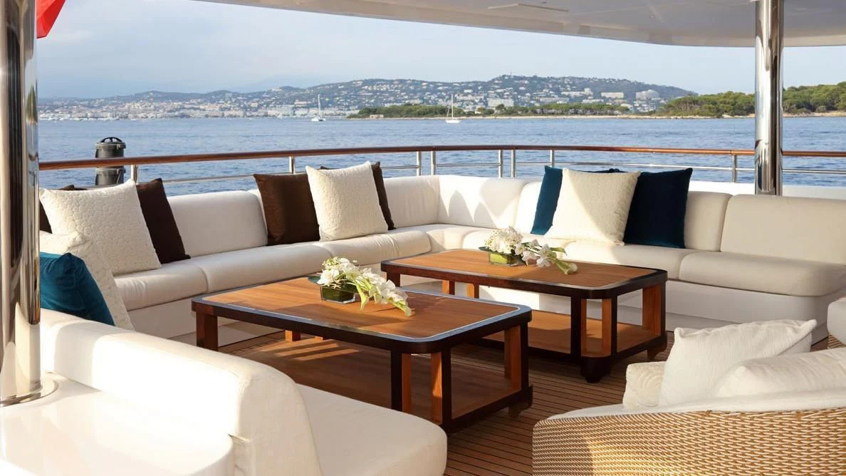 a room with a couch and a table with pillows and a view of the city aboard FORMOSA Yacht for Sale