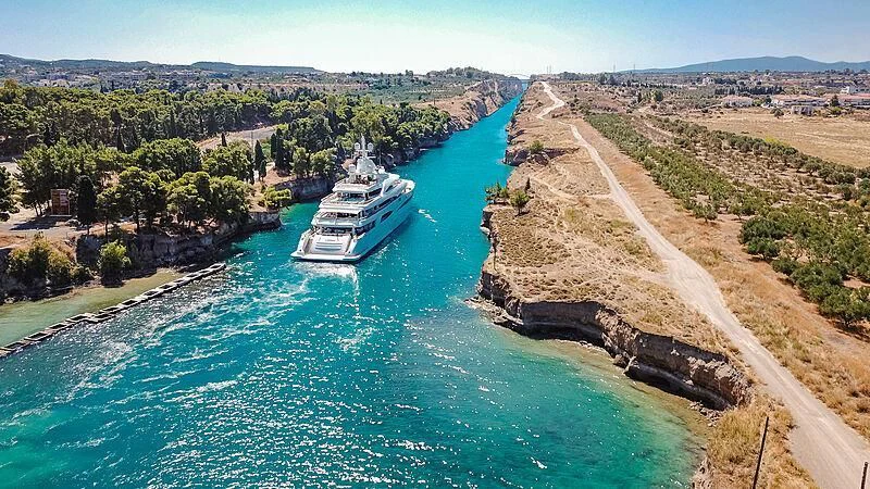 a ship sailing on a river with Corinth Canal in the background aboard MIMTEE Yacht for Sale