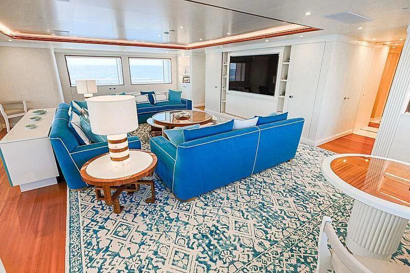 a room with a blue couch and a table with a lamp on it aboard MIMTEE Yacht for Sale