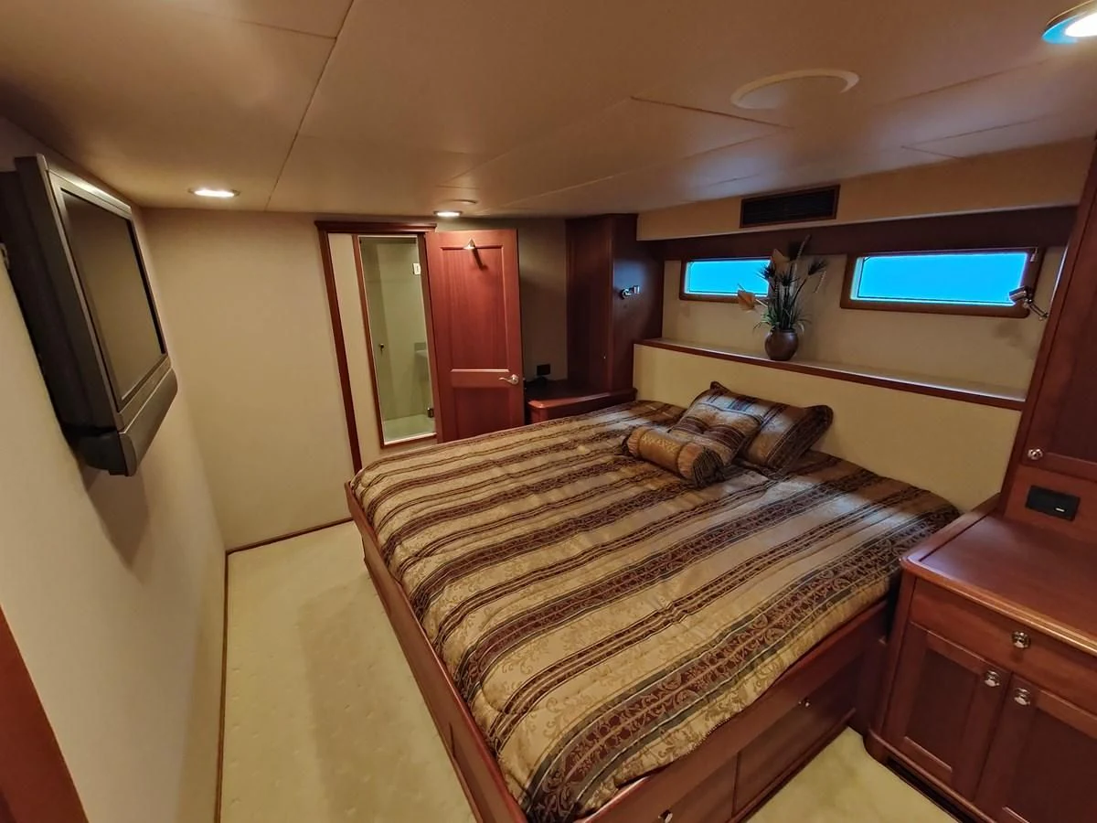 a bedroom with a bed and tv aboard SPELLBOUND Yacht for Sale