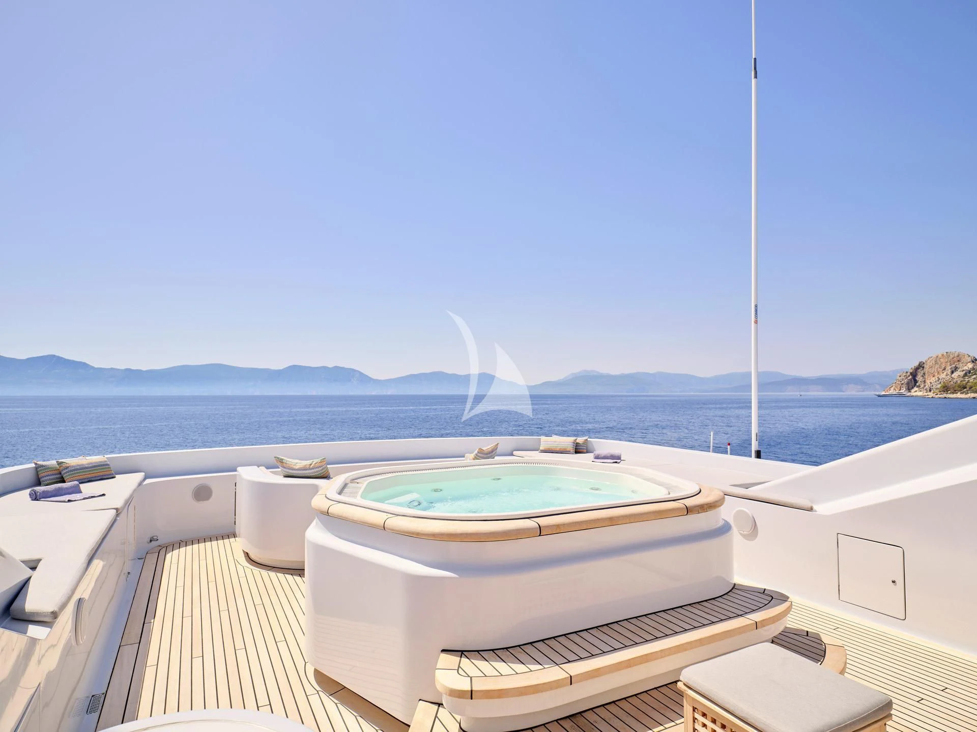 a deck with a view of the ocean and mountains in the background aboard JAZ Yacht for Charter