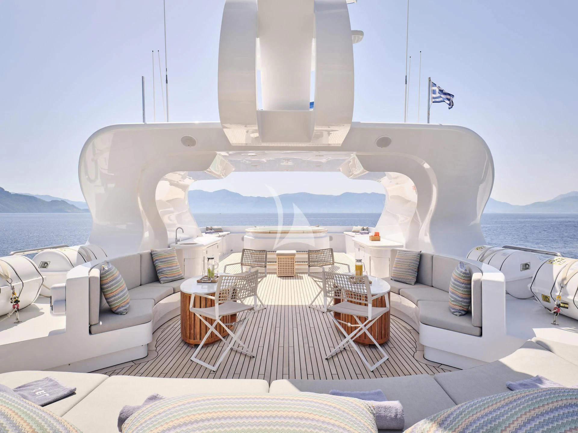 a large white bed with a white couch and a white table aboard JAZ Yacht for Charter