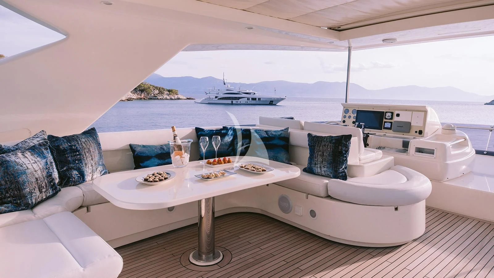 a white lounge chair with blue pillows and a white table with food on it aboard MAYBE NOT Yacht for Sale