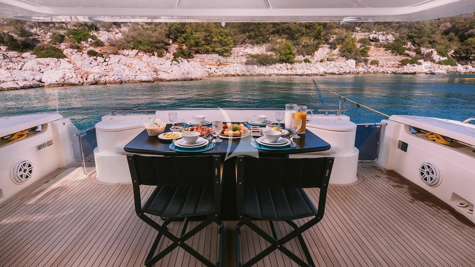a table with a chair and a chair on a deck by a body of water aboard MAYBE NOT Yacht for Sale