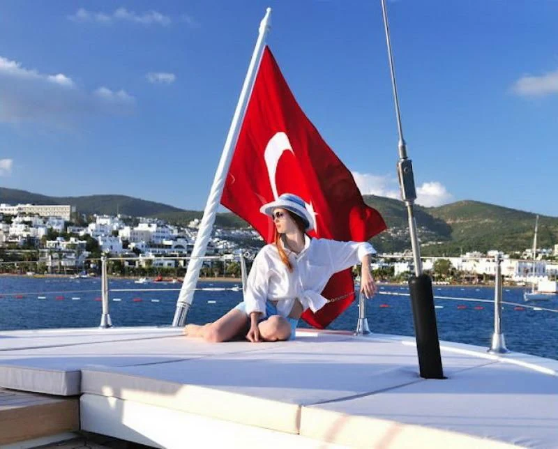 a man sitting on a railing with a flag on his lap aboard TUYIKA S Yacht for Sale