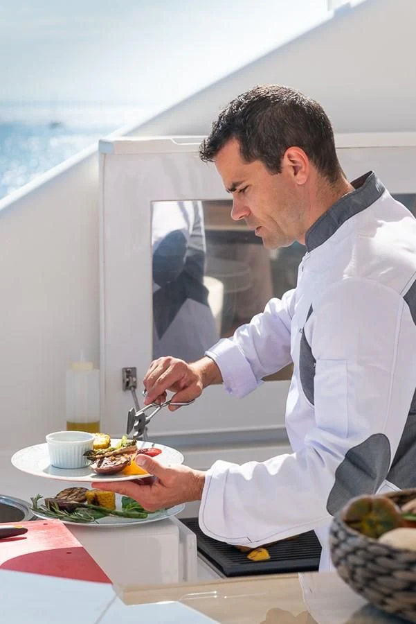 a man in a white coat aboard ELENA NUEVE Yacht for Charter