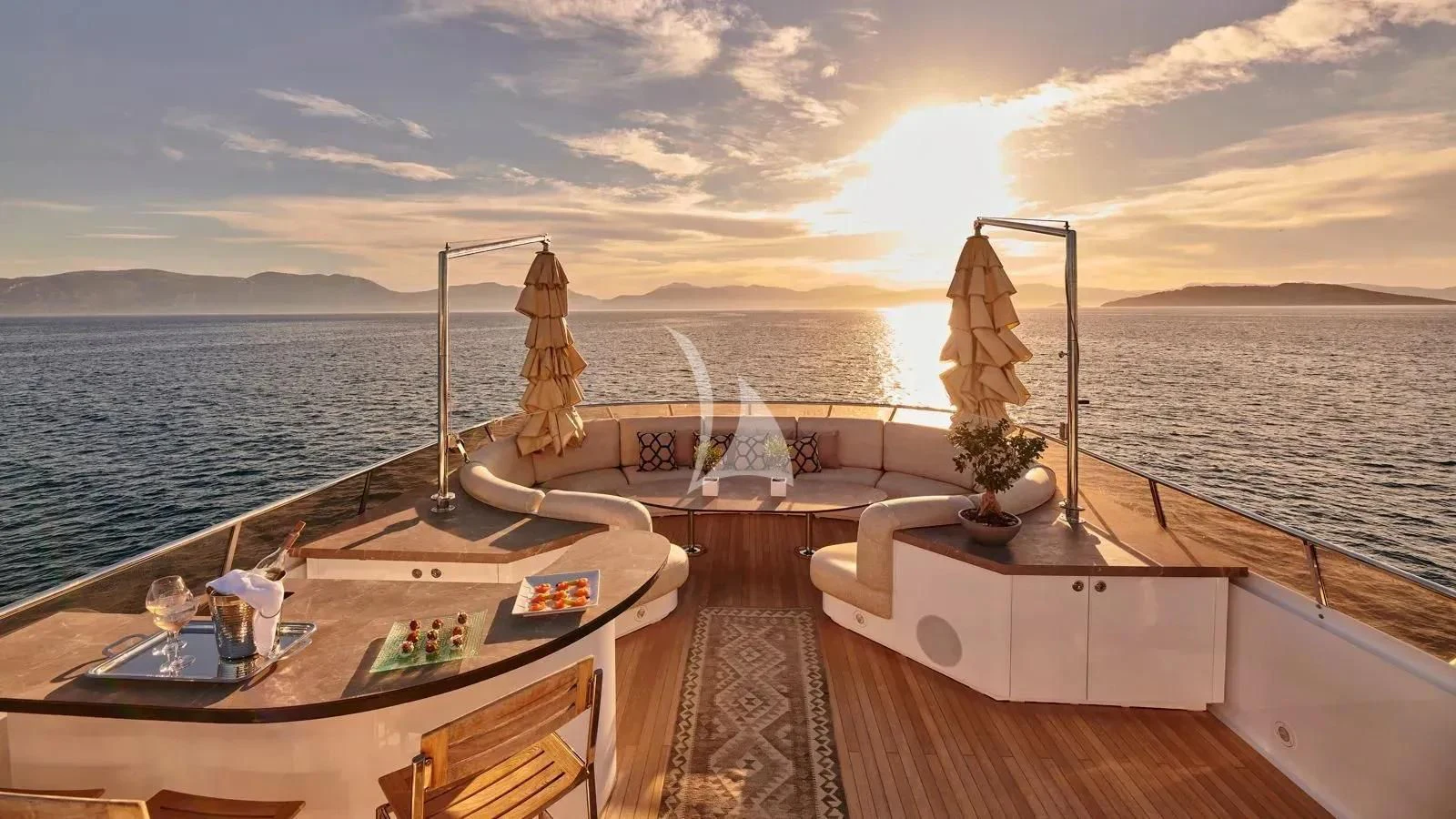a room with a table and chairs on it and a body of water in the background aboard PROMETHEUS I Yacht for Charter