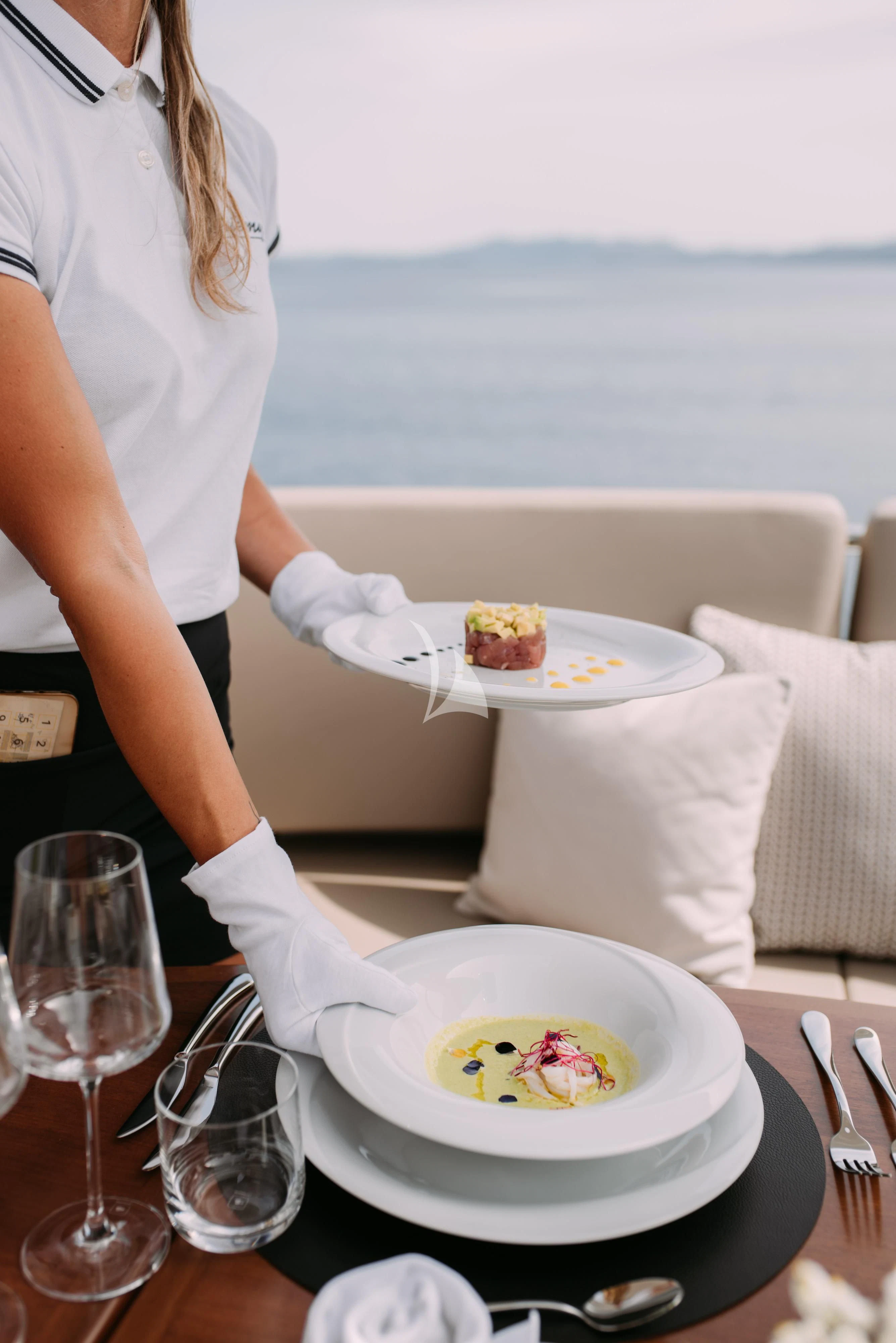 a woman in a white shirt is preparing a dish on a table aboard ARTEMY Yacht for Sale