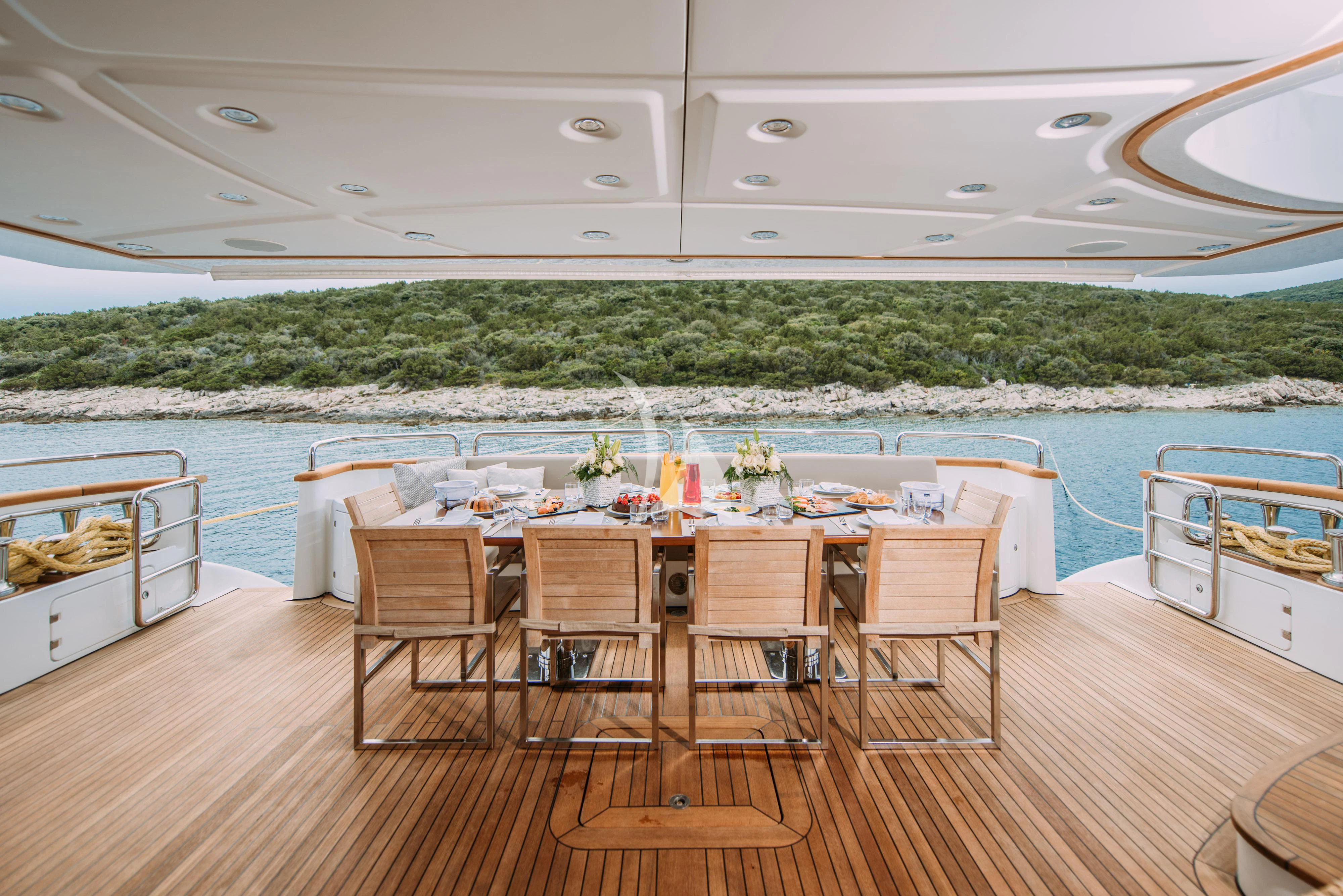 a table set for a meal on a deck overlooking a body of water aboard ARTEMY Yacht for Sale