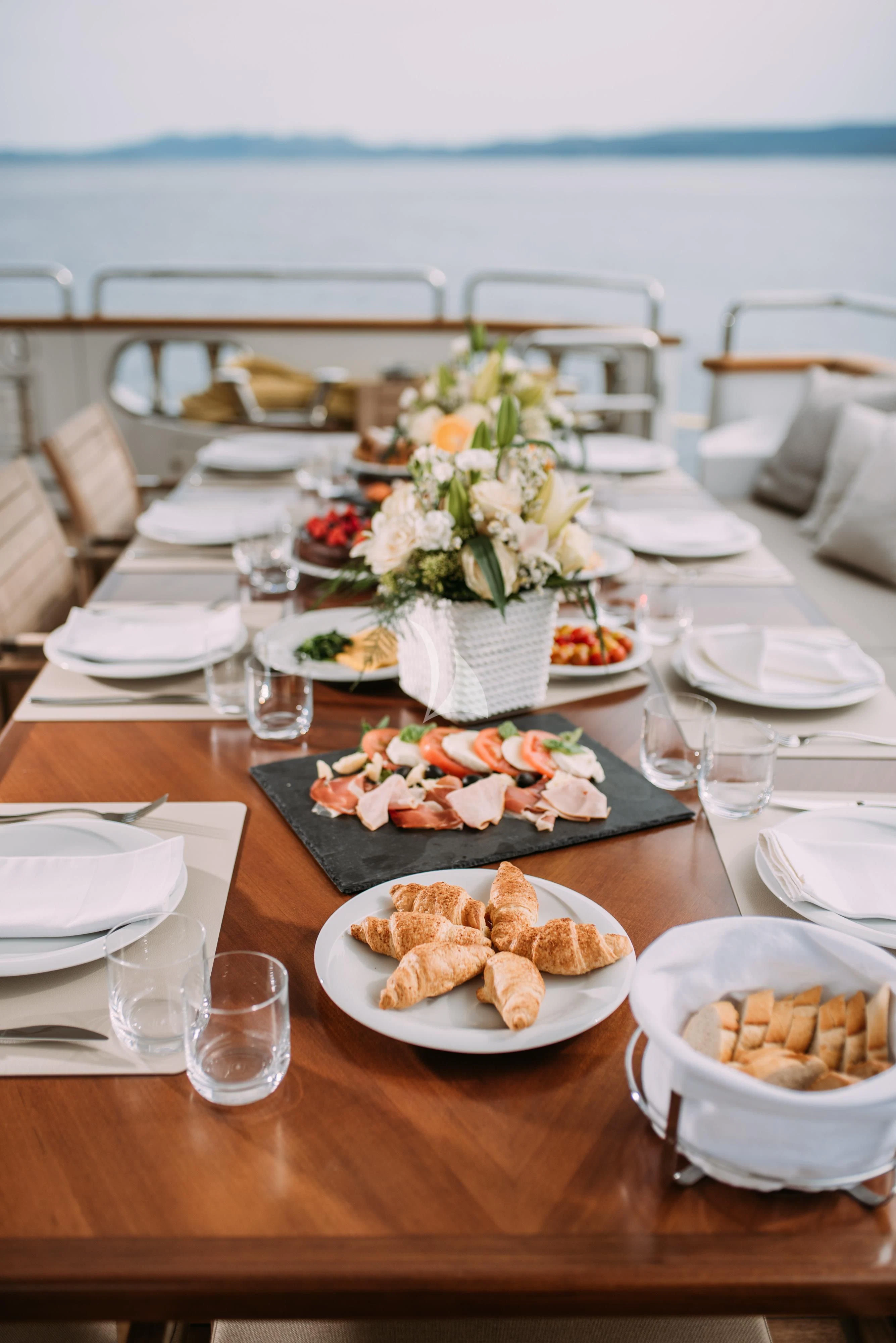 a table with plates of food and flowers on it aboard ARTEMY Yacht for Sale