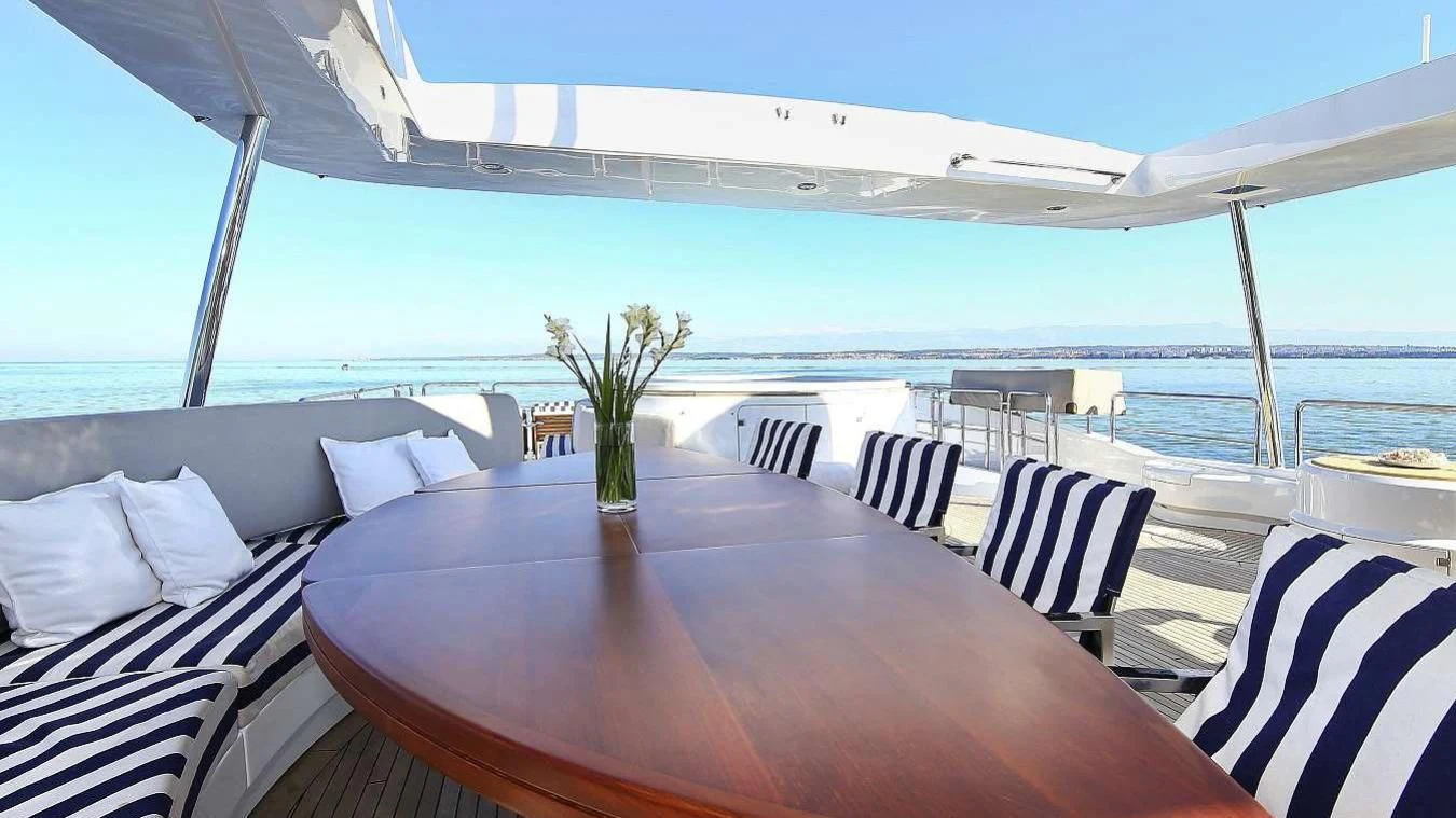 a table on a patio with chairs and a large body of water in the background aboard ARTEMY Yacht for Sale