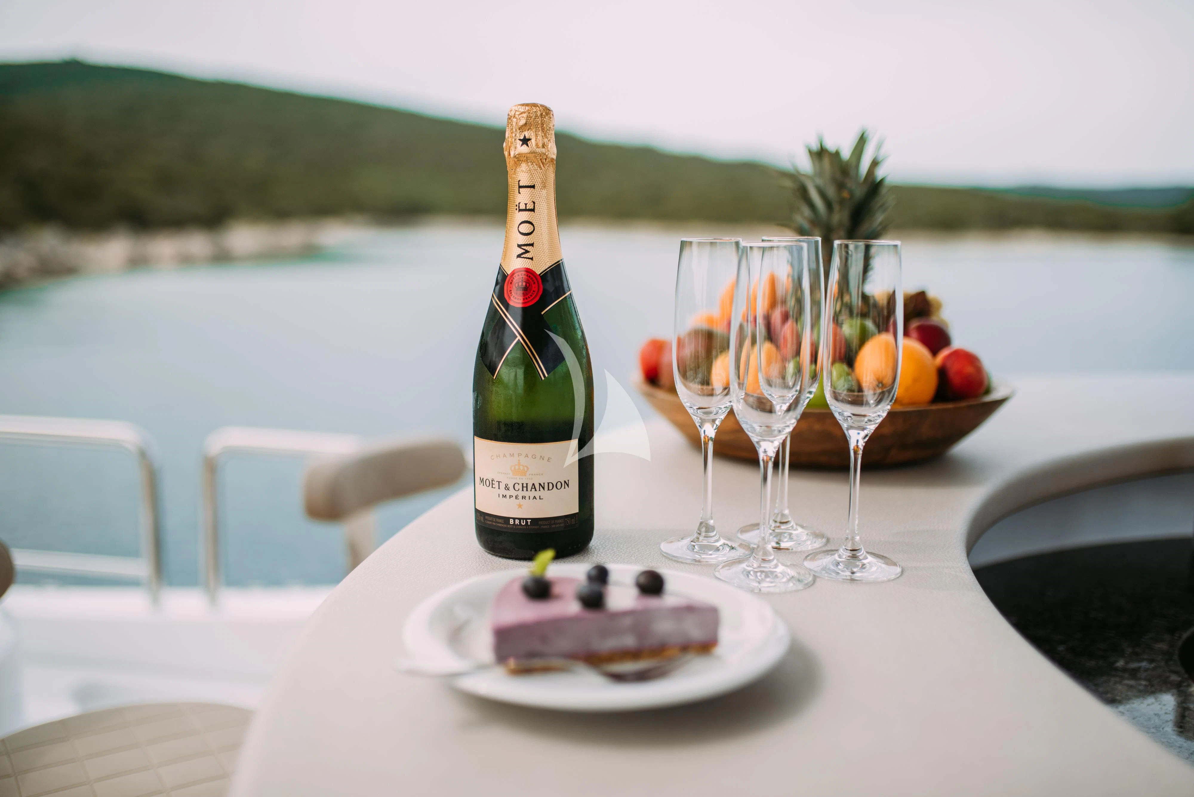 a bottle of wine and glasses on a table with a plate of food and a glass of wine aboard ARTEMY Yacht for Sale