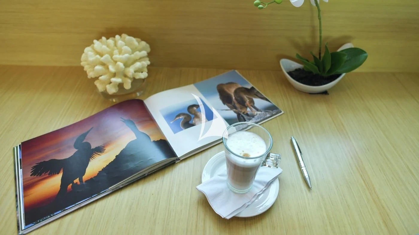 a book and a cup of coffee on a table aboard GALAPAGOS EXPLORER Yacht for Sale