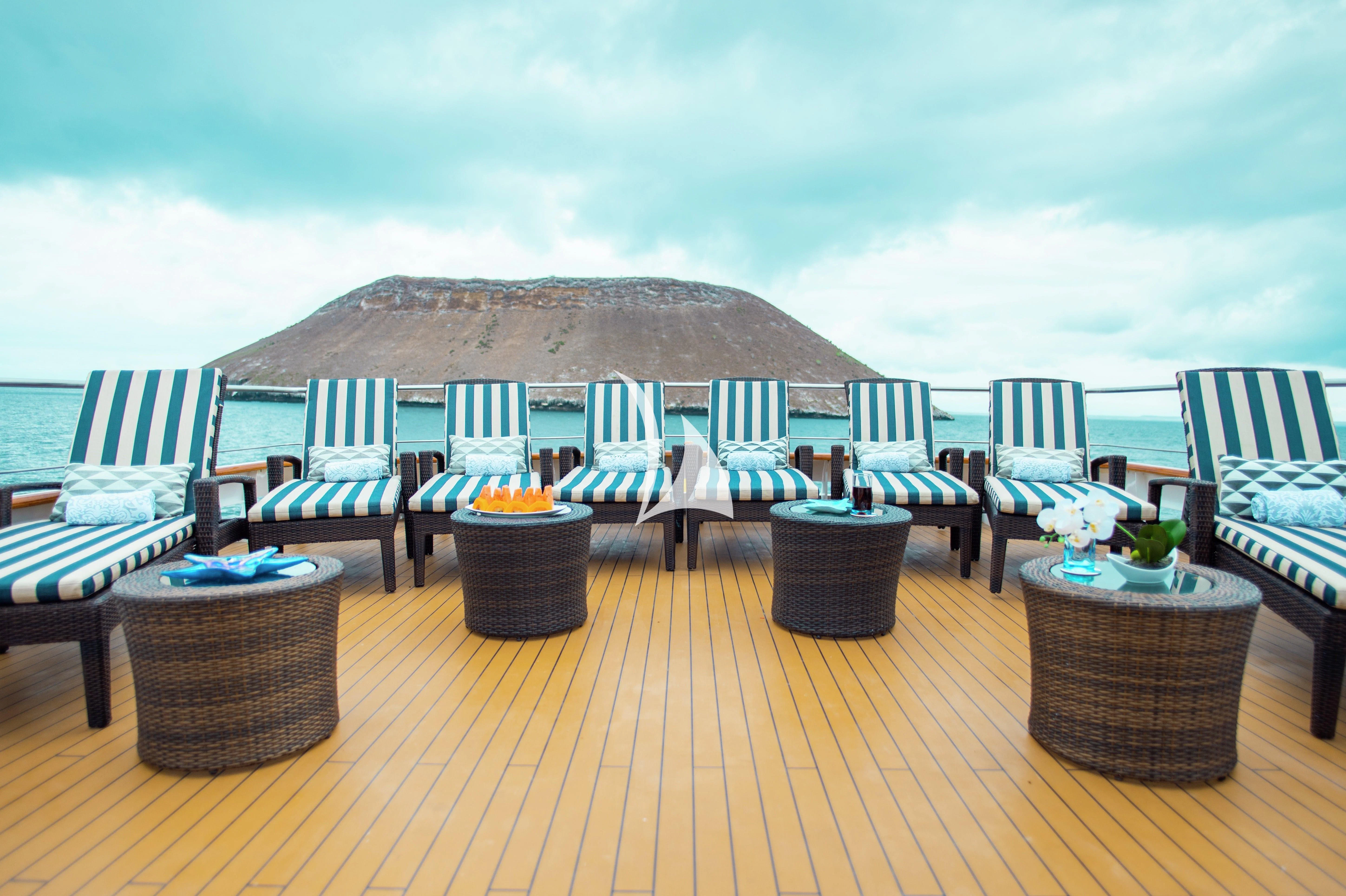a deck with chairs and tables on it aboard GALAPAGOS EXPLORER Yacht for Sale
