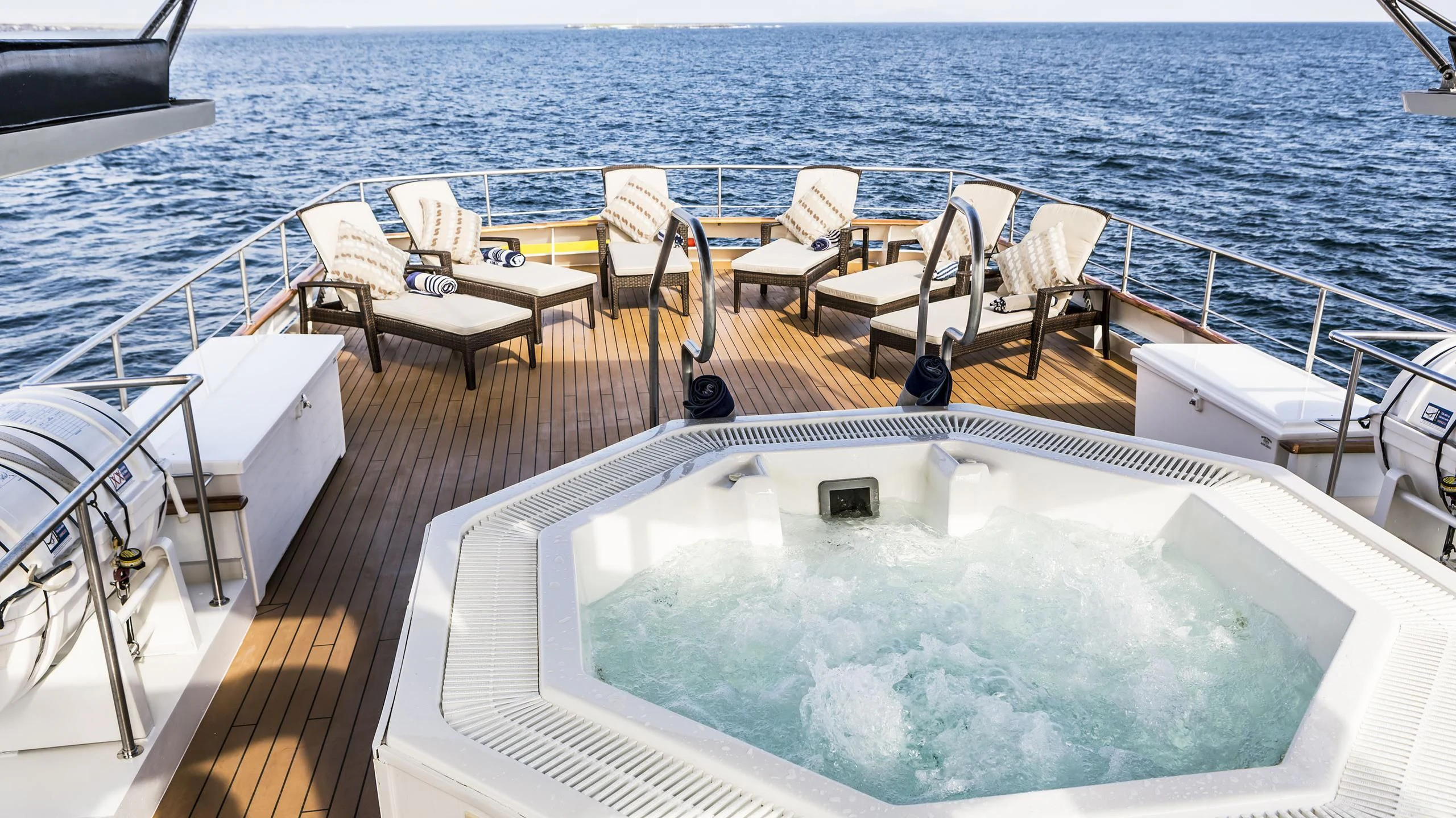 a deck with chairs and tables on it by the water aboard GALAPAGOS EXPLORER Yacht for Sale