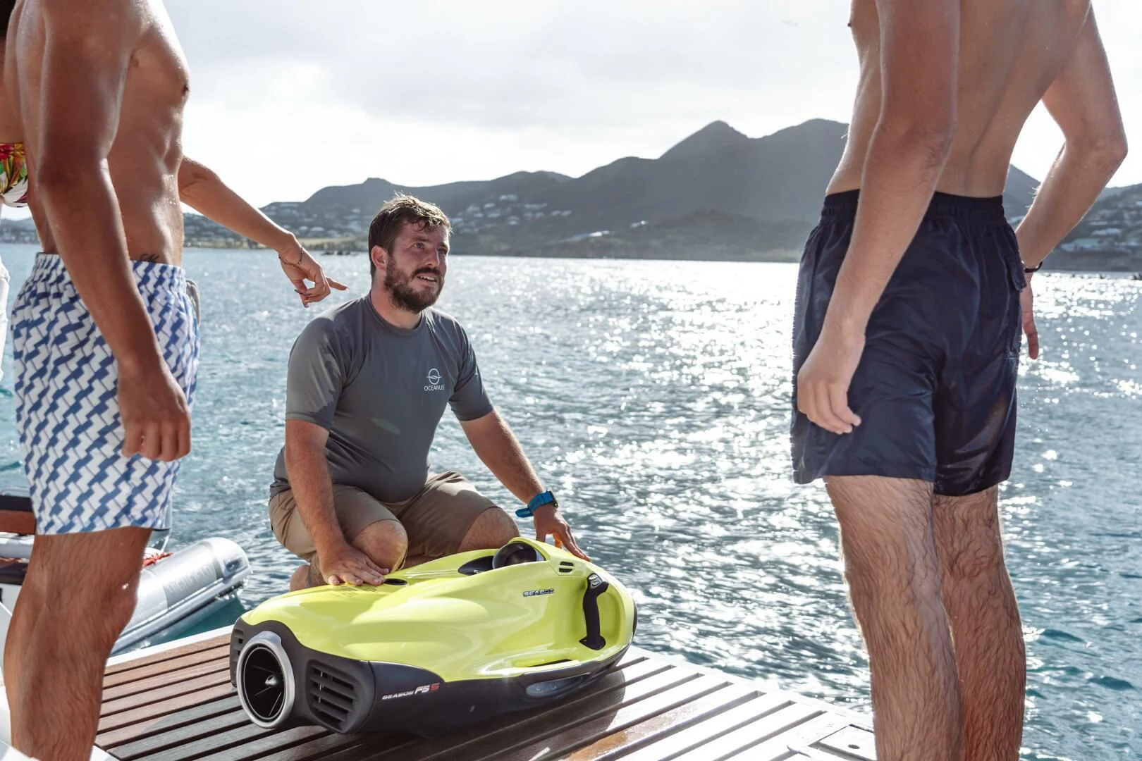 a group of men standing next to a small green and yellow boat aboard OCEANUS Yacht for Sale