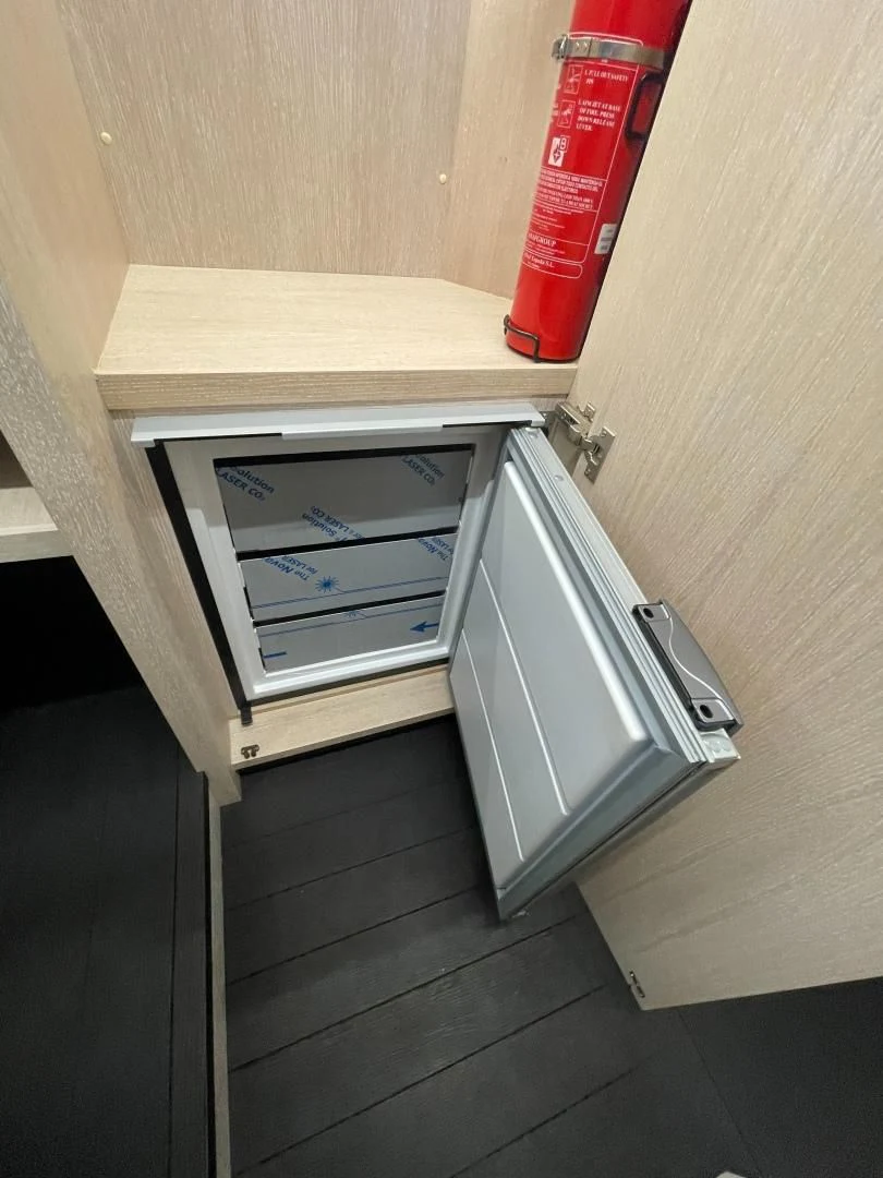 a small refrigerator in a wooden cabinet aboard AGRODOLCE Yacht for Sale