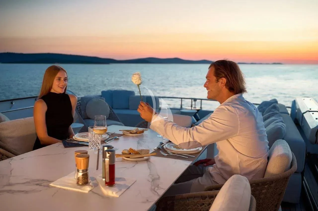 a man and woman sitting at a table with food and drinks on it aboard DAMARI Yacht for Charter