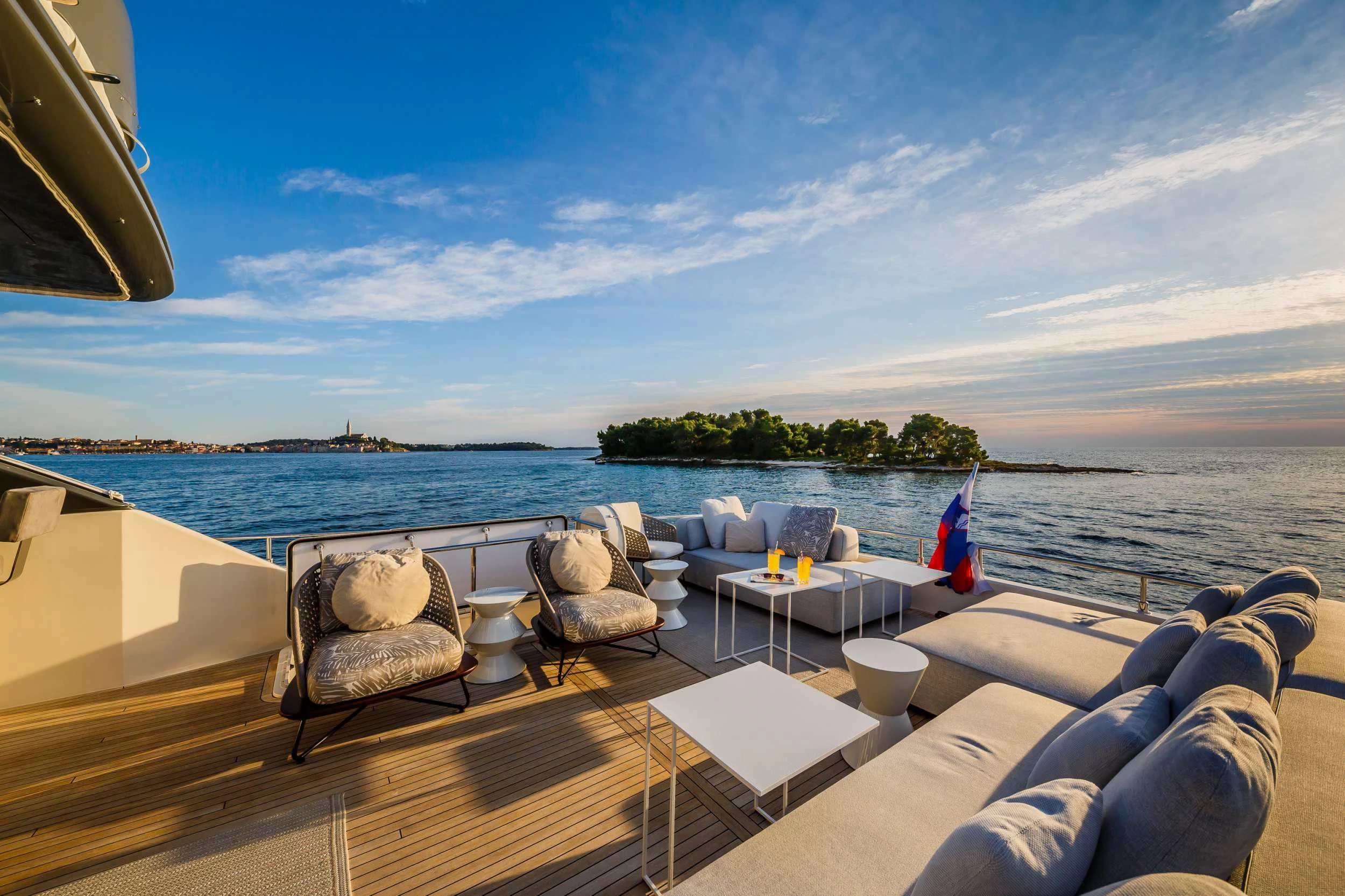 a deck with chairs and tables on it by a body of water aboard DAMARI Yacht for Charter
