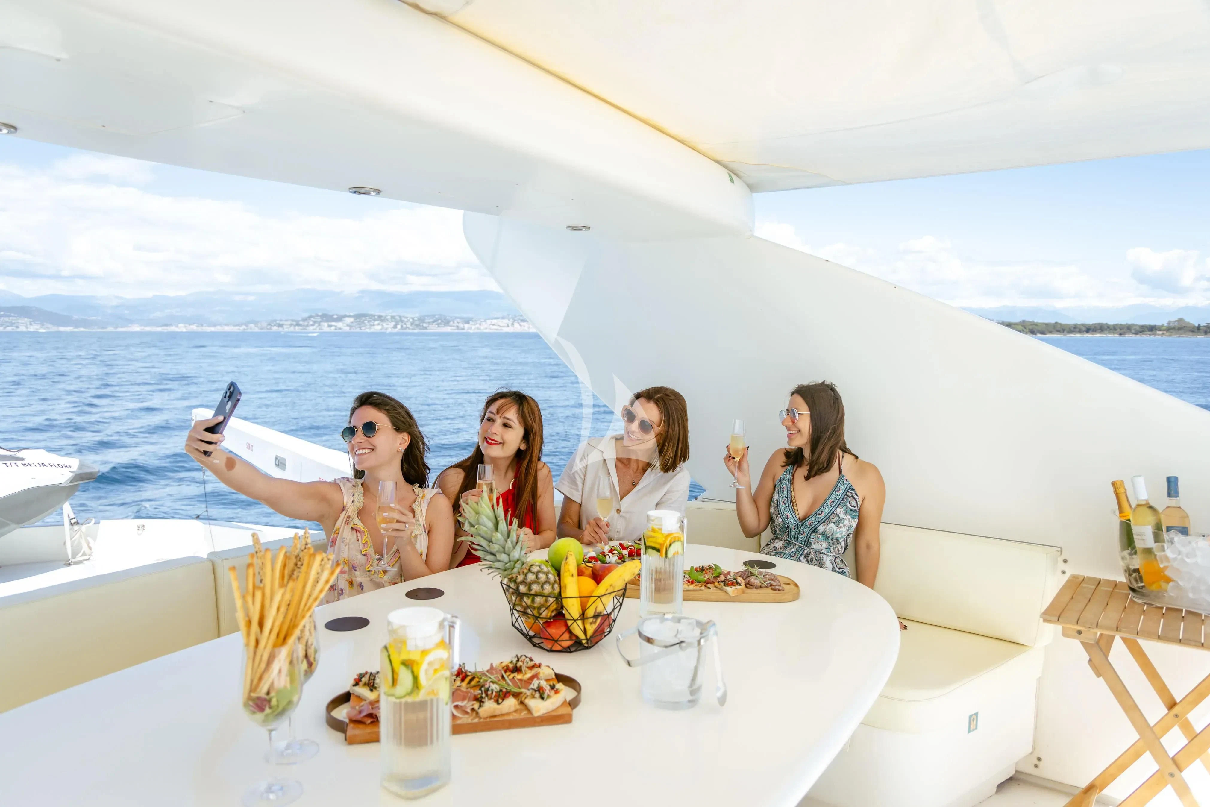 a group of women sitting at a table with food and drinks on it aboard BEIJA FLORE Yacht for Charter