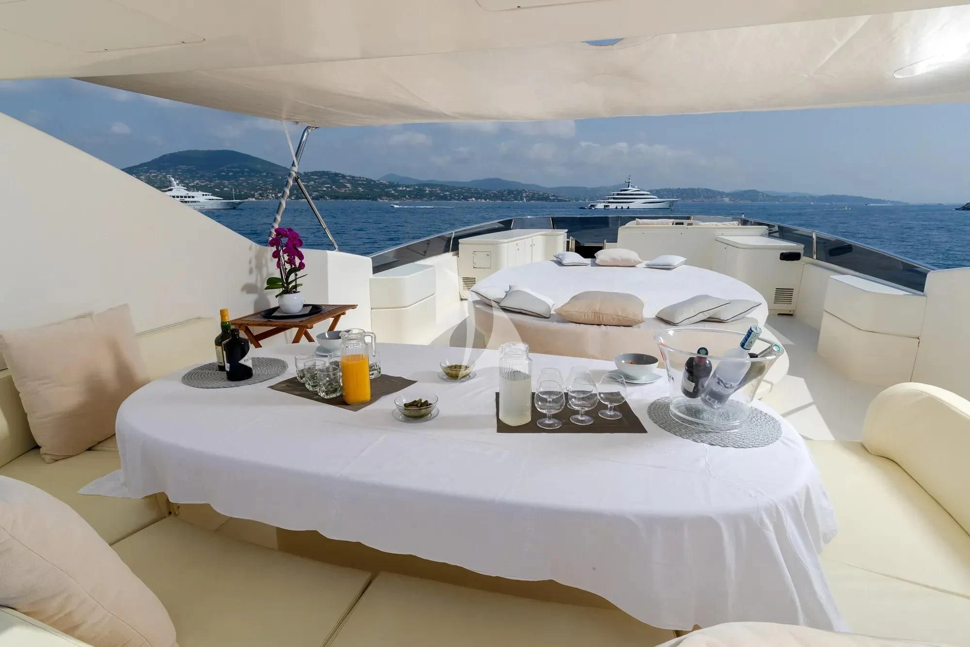 a room with a large bed and a table with chairs and a view of the ocean aboard BEIJA FLORE Yacht for Charter