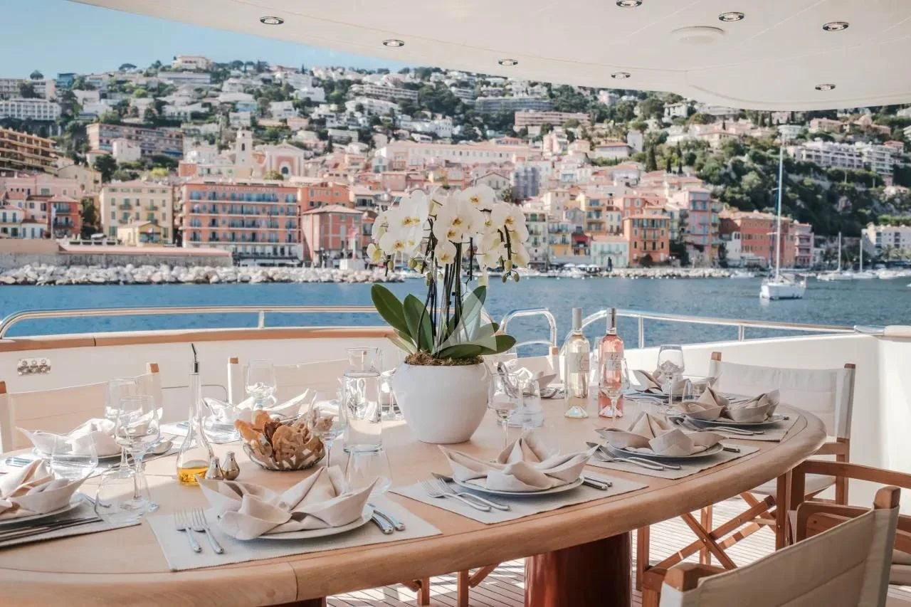 a table with plates and glasses on it with a city in the background aboard BEIJA FLORE Yacht for Charter