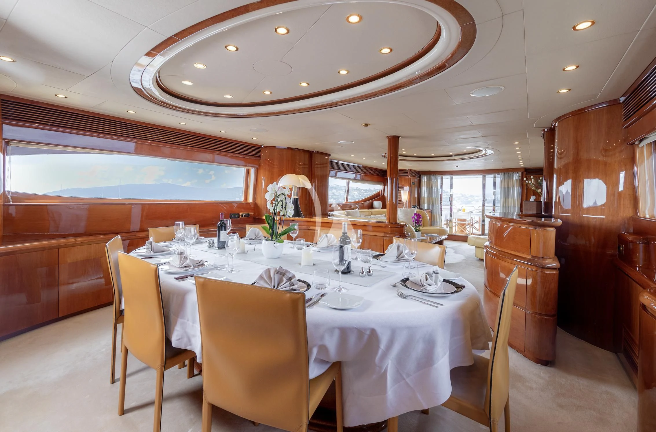 a large dining table with white cloths and chairs aboard BEIJA FLORE Yacht for Charter