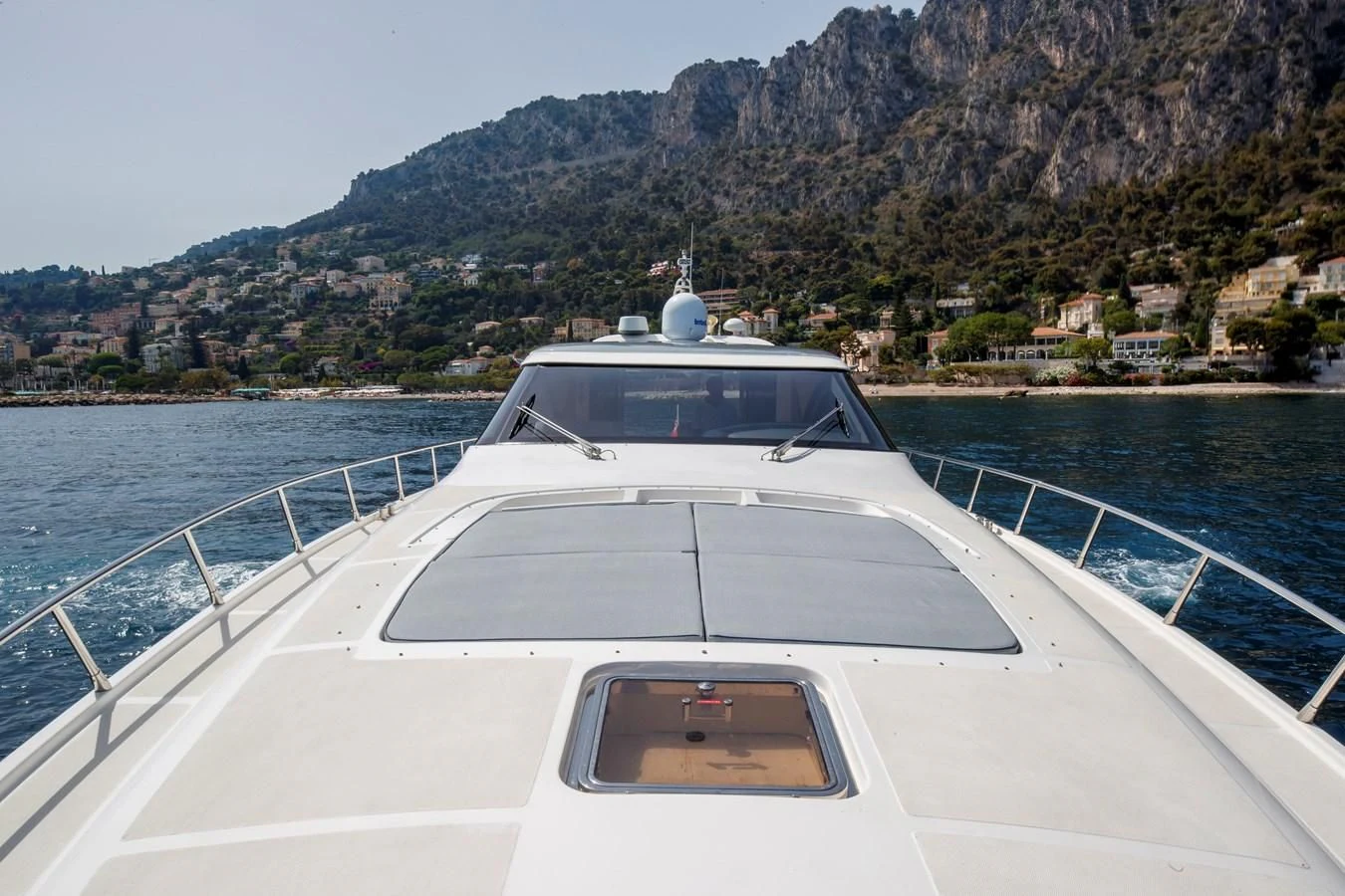 a white boat on a body of water with hills in the background aboard KOKAB Yacht for Charter