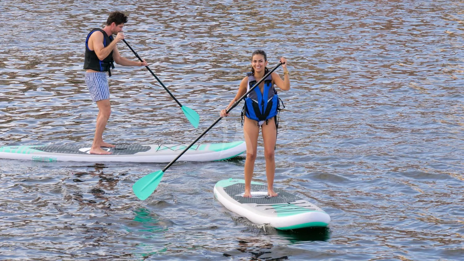 a woman and a man on a paddle board in the water aboard SWEET VIRGINIA Yacht for Sale