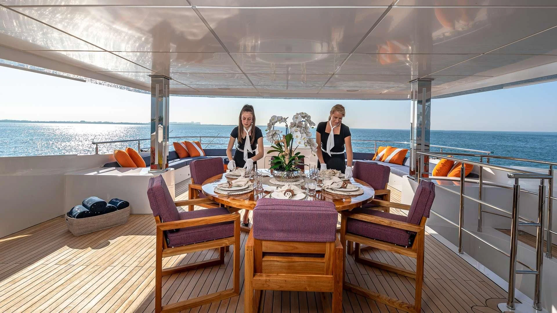 a couple of women sitting at a table on a deck overlooking the ocean aboard RISING DAWN Yacht for Sale