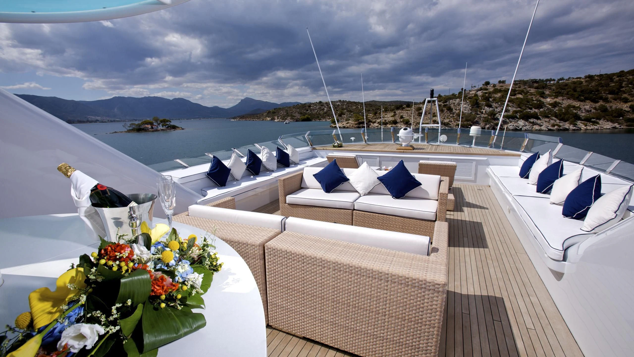a deck with chairs and tables on it by the ocean aboard ACHILLES Yacht for Sale
