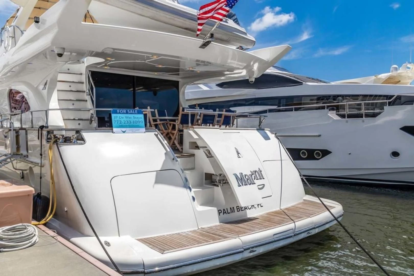 a large white boat with a flag on the deck aboard THE CURE Yacht for Sale