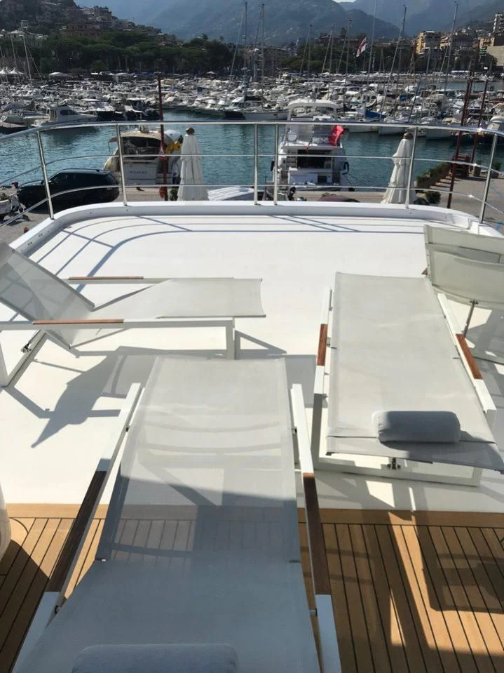 a deck with a boat and a dock with a city in the background aboard GOOD VIBES Yacht for Sale