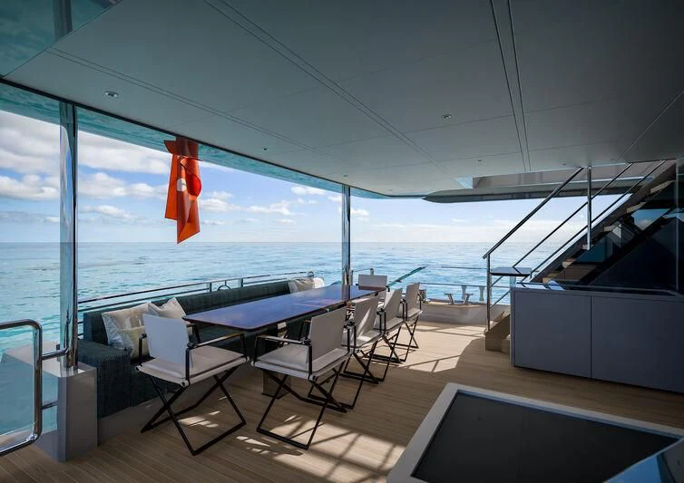 a room with a table and chairs on a deck overlooking the ocean aboard NIRVANA II Yacht for Sale