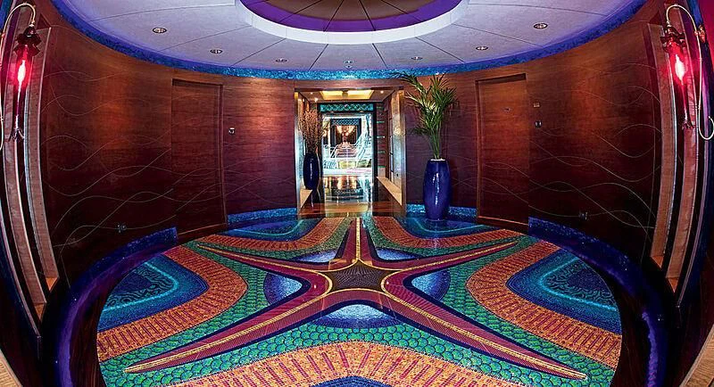 a room with a blue rug and a plant in a vase aboard SCENIC ECLIPSE Yacht for Sale