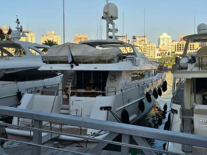 a large ship docked with HMS M33 in the background aboard AMNA Yacht for Sale